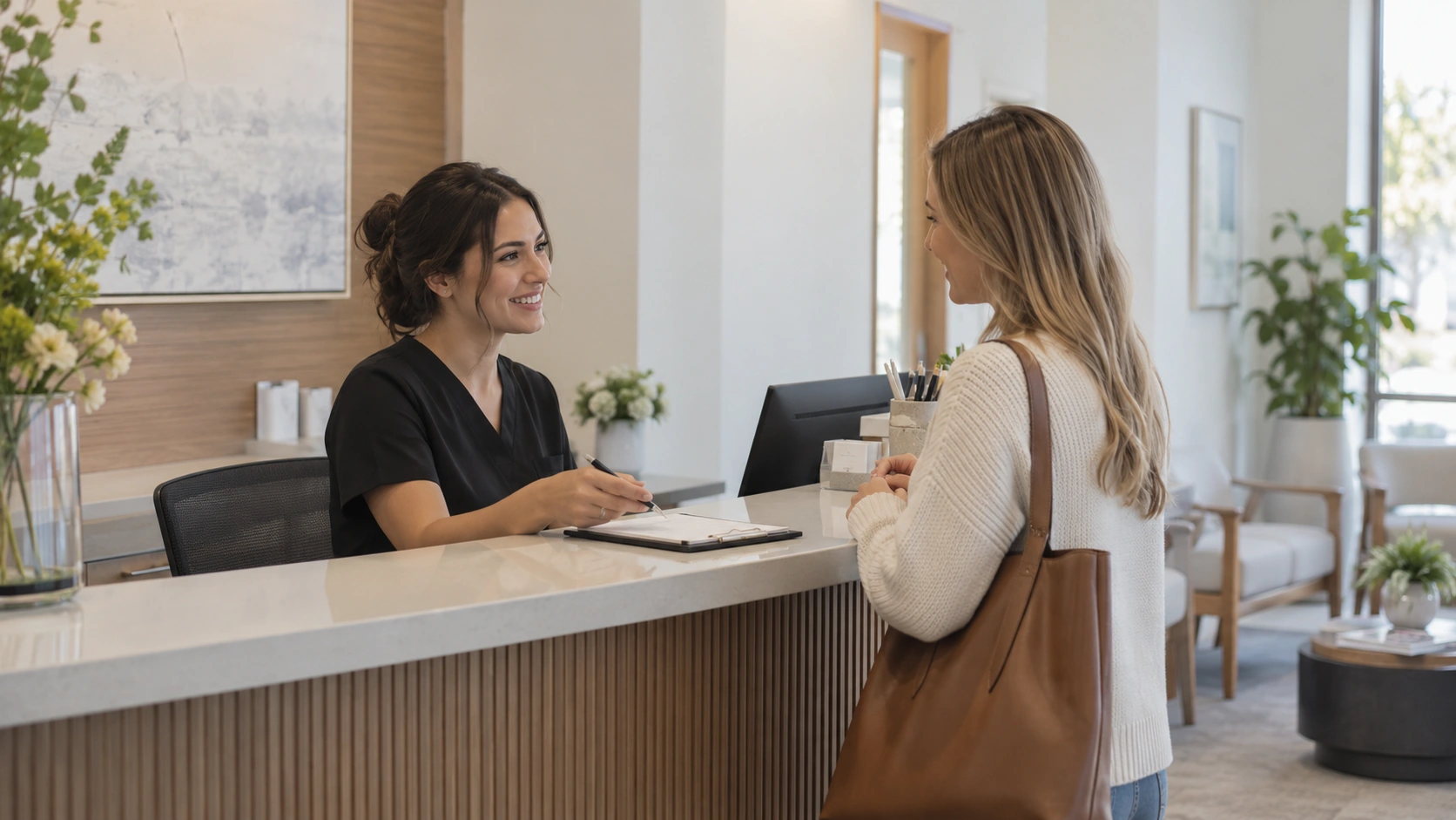 Una recepcionista conversa con una visitante en un mostrador de atención.